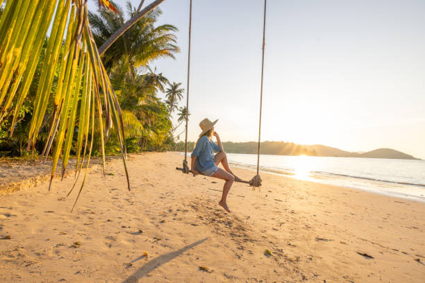 istock Woman on Beach Swing Enjoys Tropical Sunset 2192871576