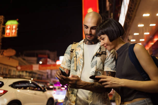 istock Traveling Couple Using Smartphones While Exploring the Bustling City Streets at Night 2192874398
