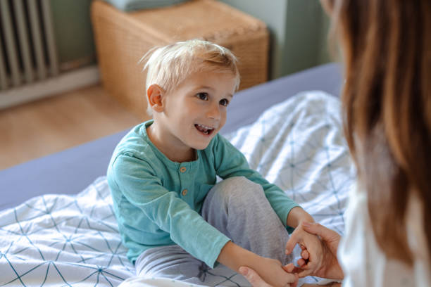 istock Young boy smiling while sitting on a bed in pajamas 2192874768