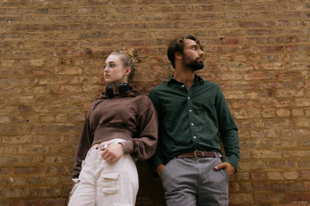 Casual Young Individuals Standing Against a Brick Wall Looking Thoughtful