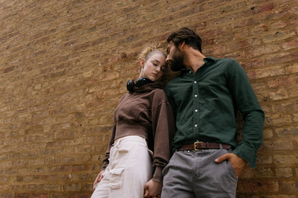 istock Casual Close-Up of a Couple Leaning Against a Rustic Brick Wall 2192875367