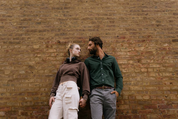 istock Stylish Young Couple Leaning on Brick Wall Expressing Confidence and Connection 2192875371