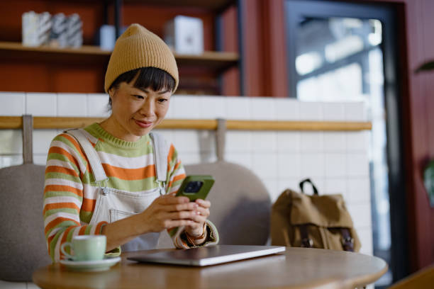 istock Woman Using Smartphone While Sitting at a Cozy Coffee Shop Cafe 2192876828