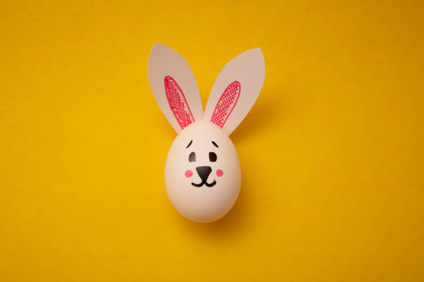 istock White chicken egg with cute rabbit face and bunny ears on yellow background 2192878835