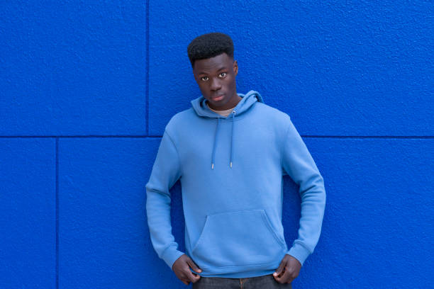 istock Young man posing with hands in pockets against a blue wall 2192879096