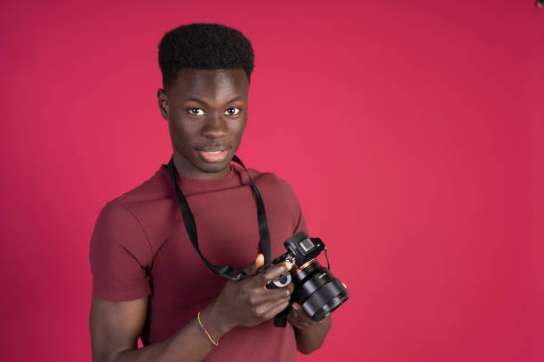 istock Young photographer holding a camera on pink background 2192879141
