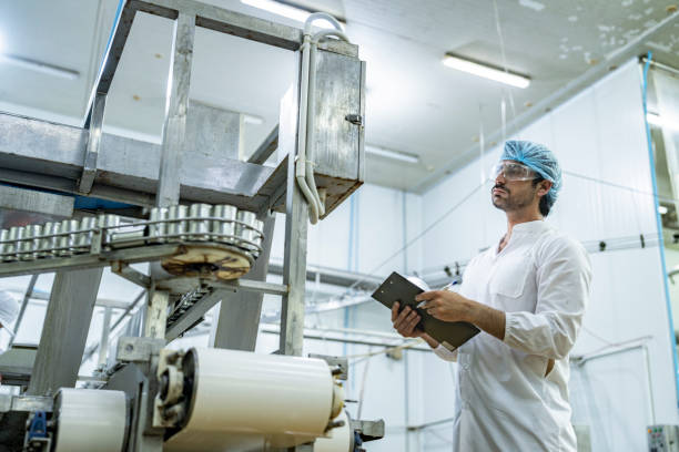 istock Professional quality control scientist inspector examining automated production lines in a modern food manufacturing facility wearing safety gear ensuring hygiene and quality standards compliance. 2192901347