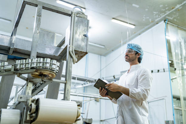 istock Professional quality control scientist inspector examining automated production lines in a modern food manufacturing facility wearing safety gear ensuring hygiene and quality standards compliance. 2192903587