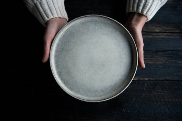 istock Woman hands holding plate over rustic wooden table. 2192903716