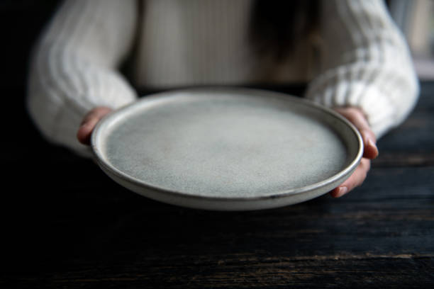istock Woman holding a  plate with both hands on a dark wooden background 2192903719