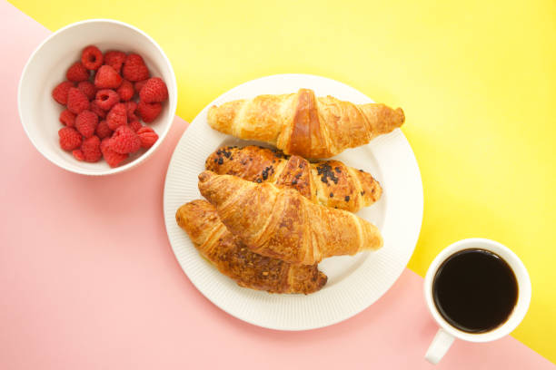 istock Coffee cup, fresh croissants and raspberries on yellow and pink background 2192907823