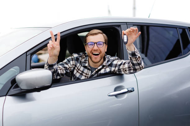 istock Excited young man showing a car key, sitting inside his new vehicle 2192908267