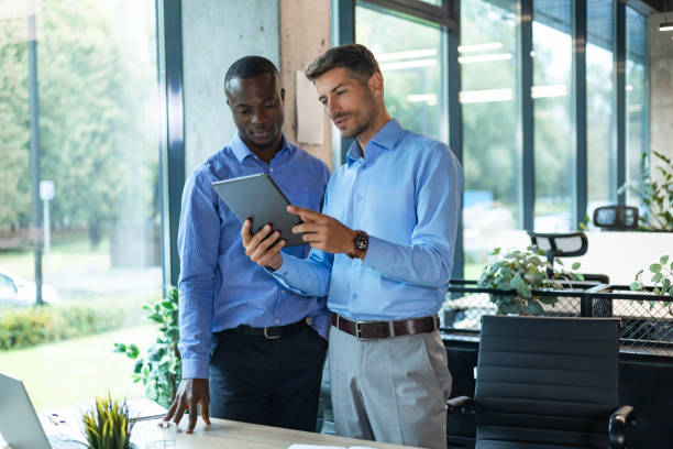 istock Two diverse business partners standing and discussing project working together at workspace 2192909344