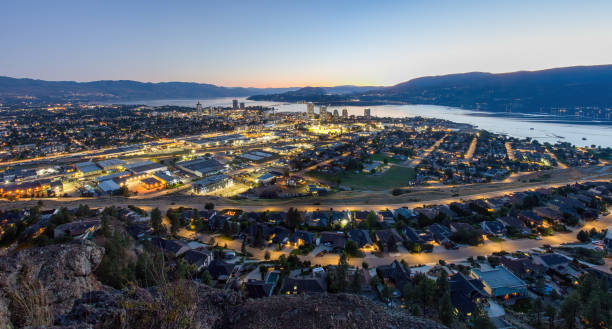 Panorama of Kelowna at sunset. Downtown Kelowna at sunset from Knox Mountain Park. Scenic view of downtown Kelowna at sunset from Knox Mountain Park, featuring the William Bennett Bridge, Okanagan Lake, and distant mountains. kelowna-autumn stock pictures, royalty-free photos & images