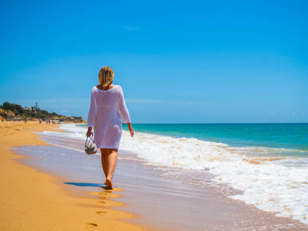 istock Beautiful mature woman walking on beach 2192916080