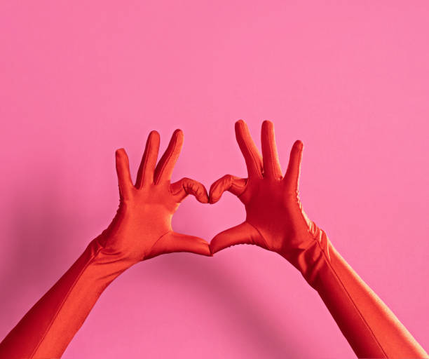 istock Hands in red gloves making heart on pink background 2192919035