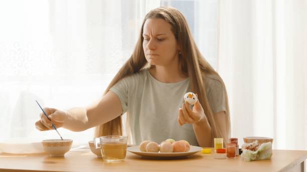 istock A Woman Reaches for More Paint While Holding a White Egg Decorated with Flowers. 2192919746
