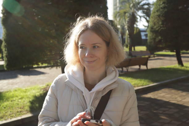 istock Woman with phone in city park, walking while holding a digital gadget, using technology for daily tasks outdoors. 2192920477