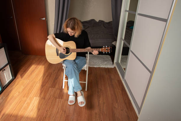 Woman playing guitar, practicing a melody with focus on technique, lifestyle of a passionate musician.