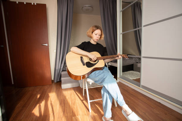 istock Woman Practicing Acoustic Guitar in Cozy Bedroom, studying musical techniques, exploring music as a playful and educational experience. 2192920543