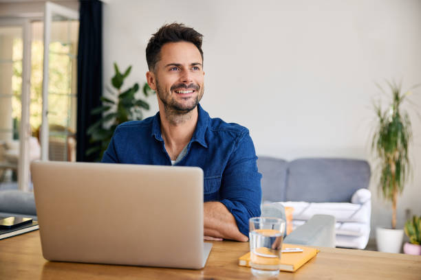istock Thoughtful man at home working on laptop looking away 2192921481