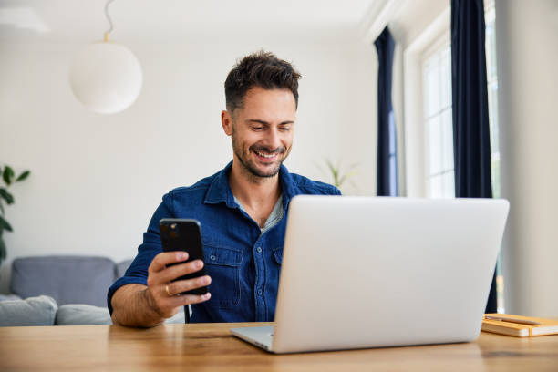 istock Happy man using phone and laptop working at home office 2192921537