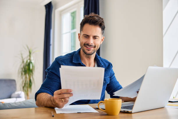 istock Happy man looking at document while working on laptop from home at living room 2192921583