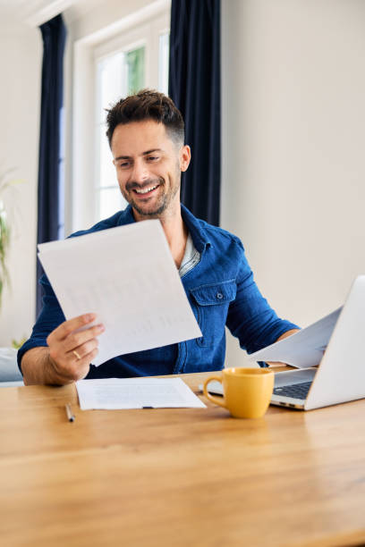istock Cheerful man looking at financial document analysing business report while working at home 2192921589