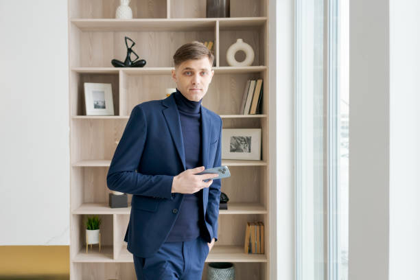 istock Man in a blue suit holding a cell phone 2192923783