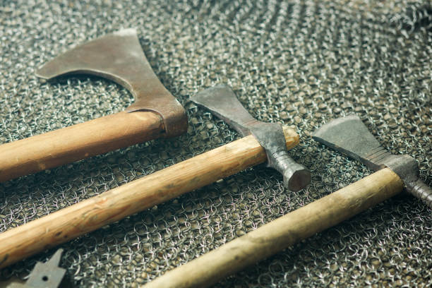Three wooden weapons are displayed on a metal mesh. The weapons are old and rusted, giving the impression of being from a bygone era. The mesh background adds a sense of mystery