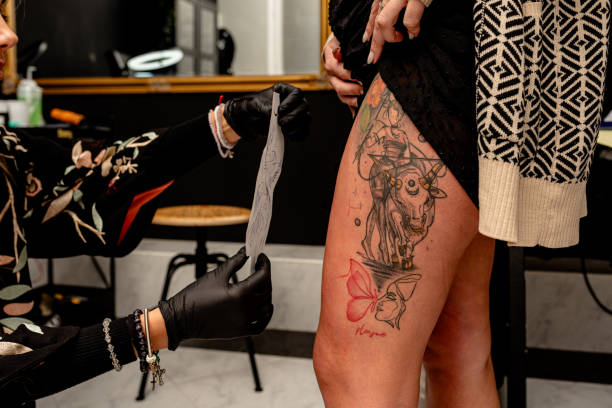 istock Tattoo artist preparing a stencil for a decorative thigh tattoo application 2192927617