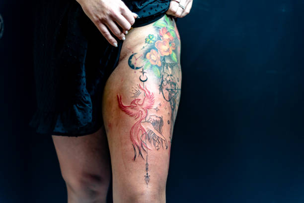Colorful floral and phoenix tattoo design on visible upper thigh