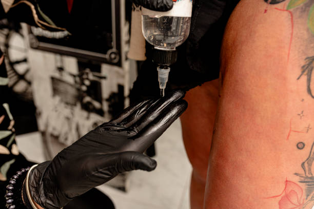 istock Tattoo artist applying pre-tattoo solution on a client's skin in studio 2192927730