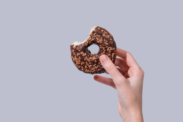 istock Hand holding glazed chocolate bite donut on blue background. 2192929654