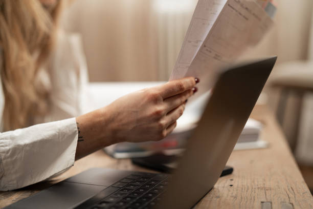 istock Woman holding financial documents at table with laptop in home office 2192932375