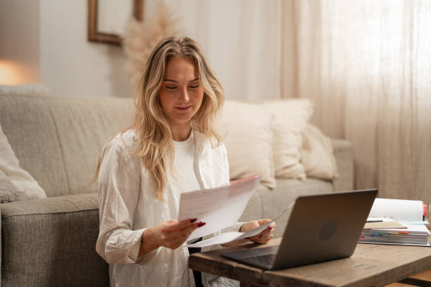 istock Confident female freelancer reading financial documents with laptop at home 2192932388