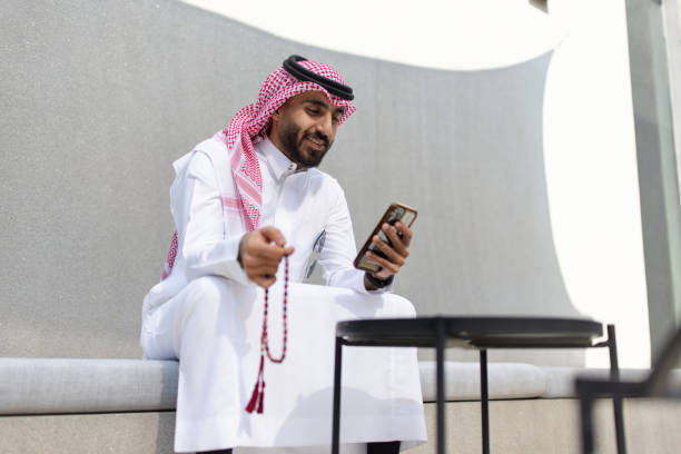 istock Arab professional holding prayer beads and using mobile phone 2192933451