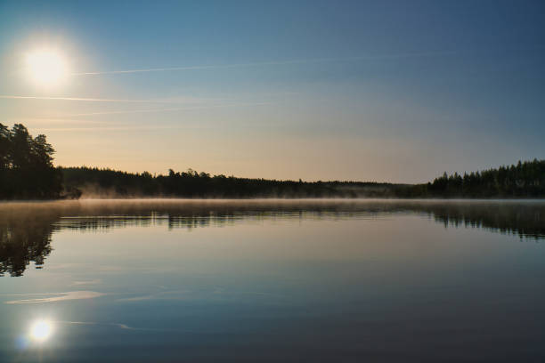 Lake in Sweden, mirror-smooth water with romantic light and trees on the shore. Scandinavian nature in the north