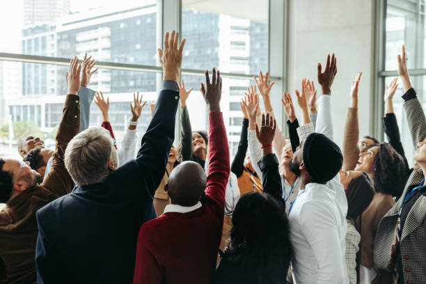 istock Unity in corporate success as diverse team celebrates achieving goals with hands raised in a modern office setting. 2192946046