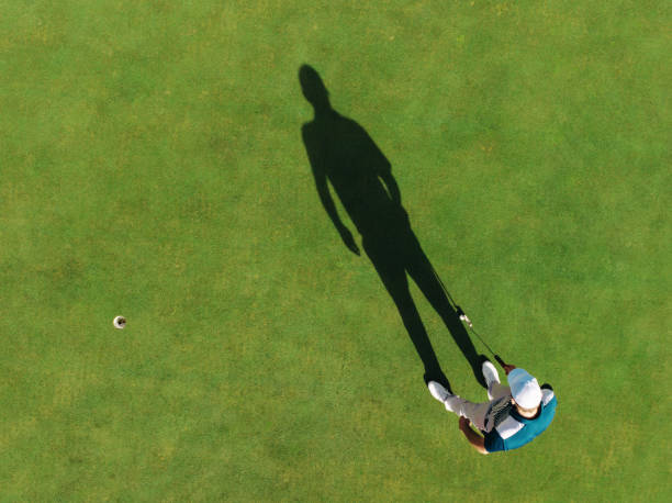 istock Aerial view of a golfer casting a shadow next to a hole on the green 2192946591
