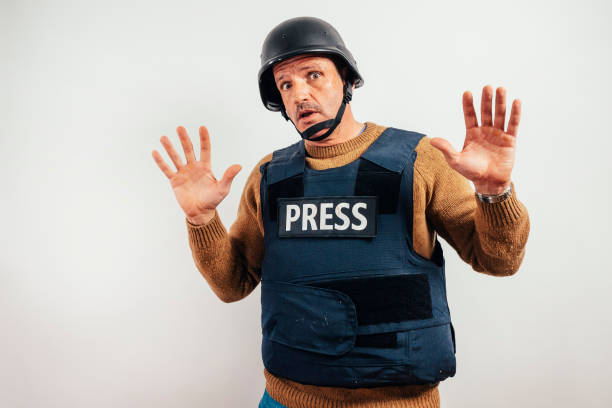 Reporter with bulletproof vest showing hands.
