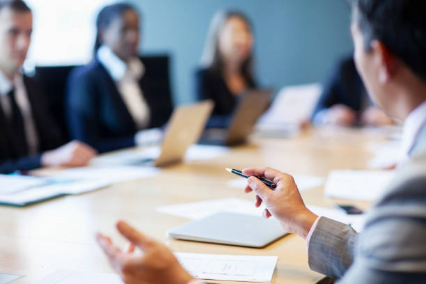 istock Hands of businessman gesturing ideas decisions with pen pointing leadership to work colleagues in business meeting at board room conference table 2192948587