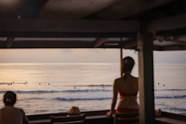 Young woman is watching to sunset view at Uluwatu beach, Bali Island - Indonesia.