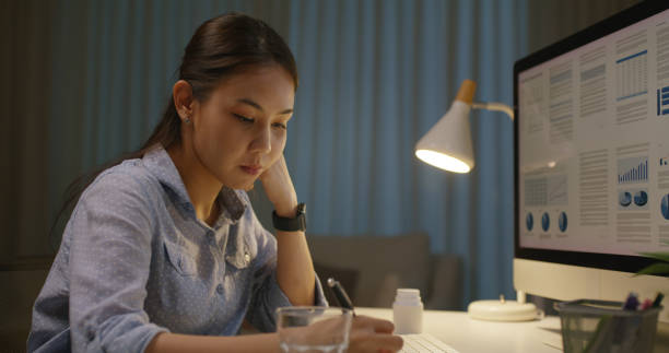 istock Young people asia workforce staff work hard late night sit on desk take pill self cure stress relief at home office. Bad sick tired female freelance worker pouring drug from bottle drink glass water. 2192949047