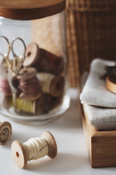 istock sewing threads on vintage rustic wooden spools with other accessories in jar 2192952373
