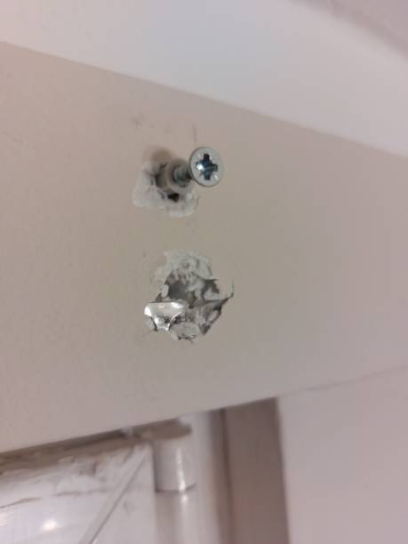 A nail in the wall and wrongly drilled hole in the wall.