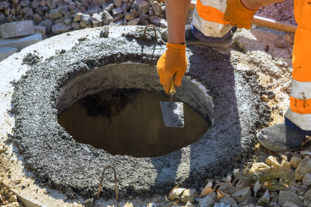 istock Fresh concrete is applied to fasten blocks forming upper boundary of manhole for a underground infrastructure 2192960468