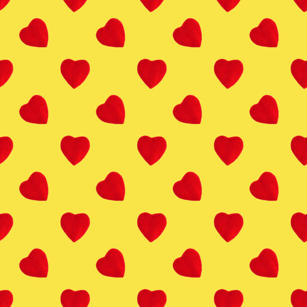 Seamless pattern made of isolated red hearts on yellow background. Top view. Flatlay. Holiday concept. Valentine's Day.