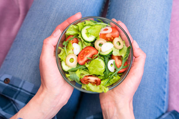 istock Women's hands hold a bowl of dieting vegetable salad. Top view. Selective focus. 2192960951