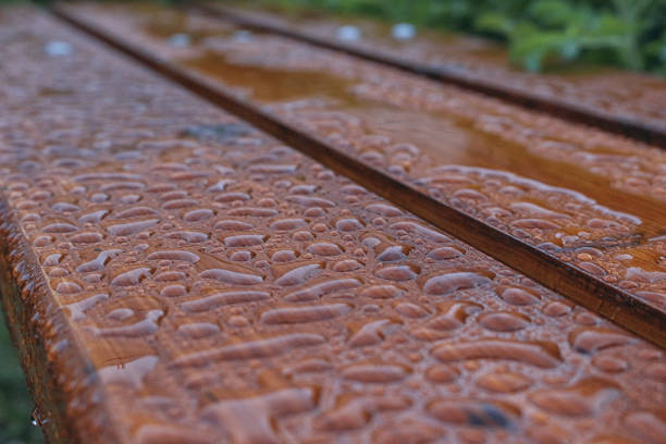 Surface in drops after rain. Droplet of water on wood after rain. Pattern of water droplets on a brown wooden surface. \n\nWood background with water drops